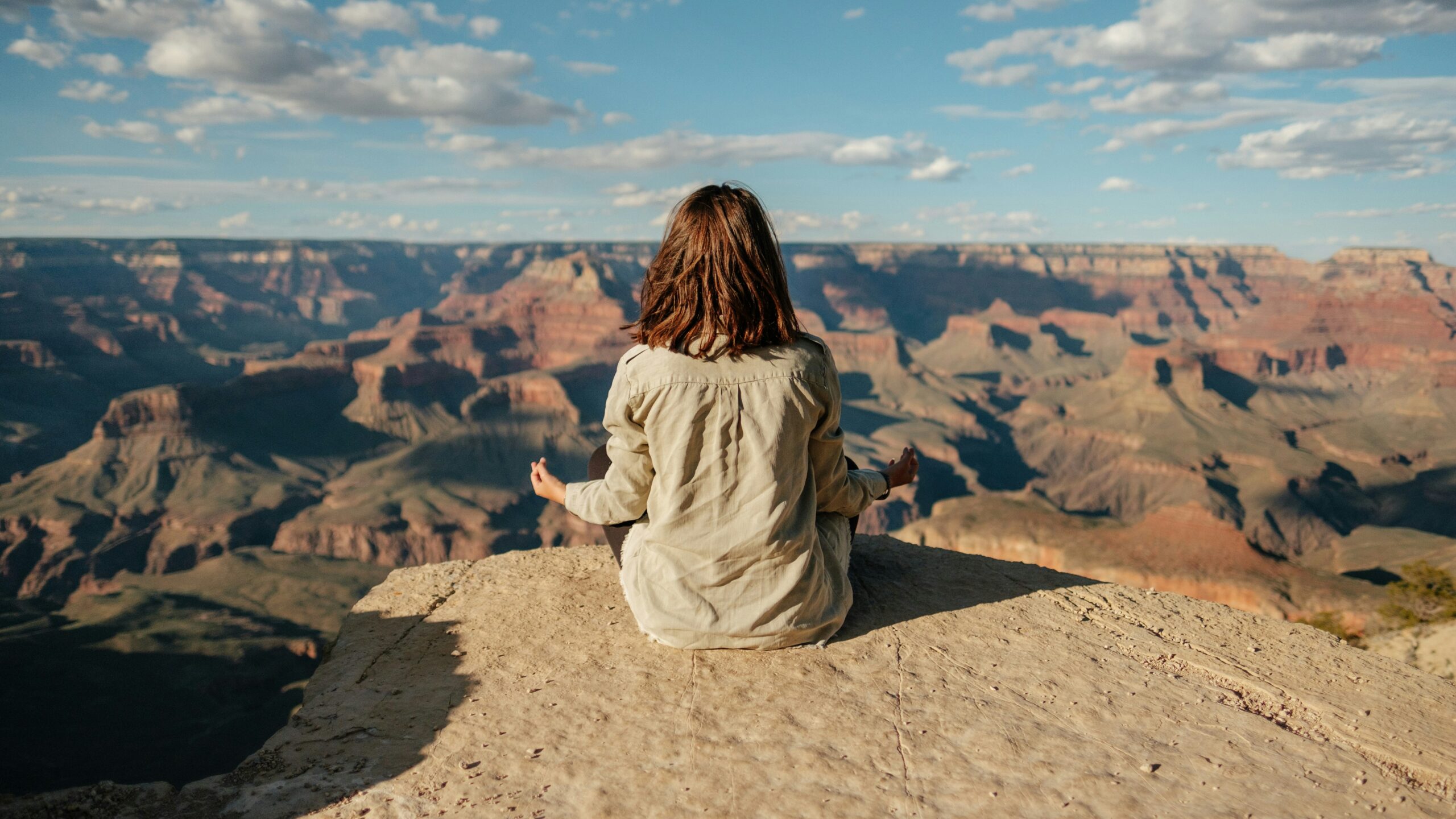 Person meditating overlooking a canyon at sunset